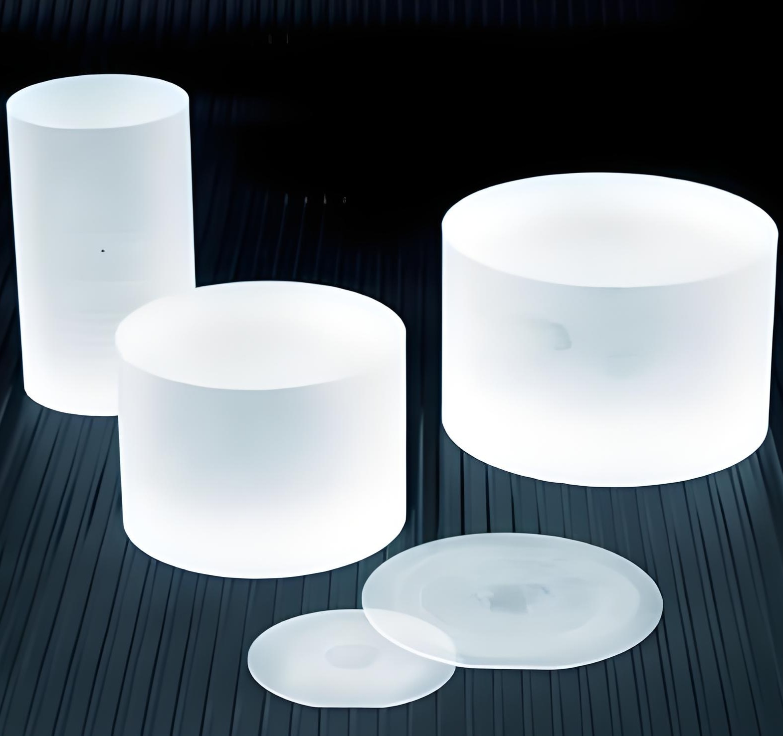 Sapphire (Al2O3) single-crystal boules and ingots alongside thin wafer slices, showing raw material before dicing